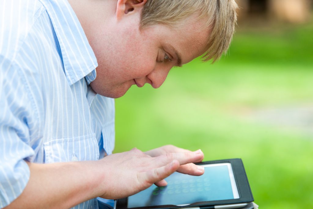 a man sitting outside using a tablet. 